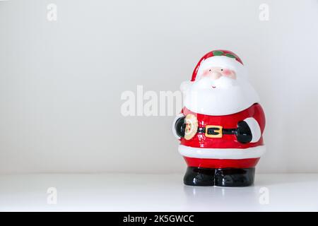 Weihnachtsmann Figur steht schräg nach links Dekoration weißen schneebedeckten Hintergrund des Hauses Interieur, kopieren Raum auf der linken Seite Stockfoto