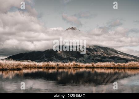 Ruhiger See umgeben von feinen weichen Pflanzen in der Nähe der Spitze des großen Berges Blick über die niedrigen Wolken und Sturm bedeckt die Vorberge, taranaki, neu Stockfoto