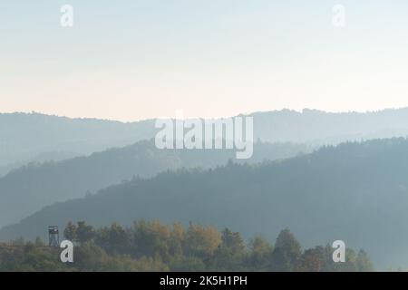 Hunter Aussichtsturm auf Hügel gegen Hügelschichten im Nebel, Herbstsaison auf dem Land Stockfoto