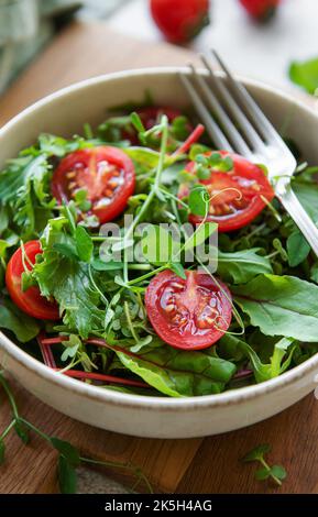 Veganes Essen: Gesunder Salat mit frischem Gemüse. Salat mit Rucola und Kirschtomaten. Stockfoto