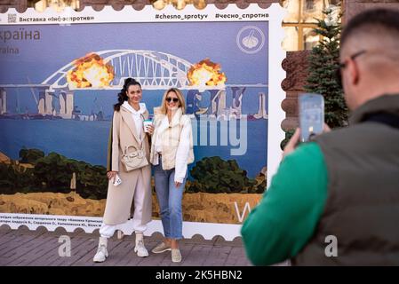 Kiew, Kiew, Ukraine. 8. Oktober 2022. Die Menschen posieren auf der Briefmarke mit dem Bild der Zerstörung einer ''Krimbrücke'', die von den Russen auf der besetzten Krim gebaut wurde. Am 8. Oktober wurden mehrere Abschnitte der Brücke zerstört und ein Zug mit Treibstoff, der sich auf dem Eisenbahnteil der Brücke bewegte, wurde in Brand gesetzt. Russland annektierte die Krim 2014. Russland begann am 24. Februar 2022 mit der umfassenden Invasion der Ukraine. (Bild: © Danylo Antoniuk/ZUMA Press Wire) Stockfoto