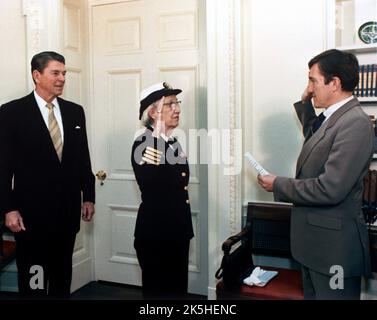 Der Navy-Sekretär John Lehman, rechts, befördert Capt. Grace Hopper in einer Zeremonie im Weißen Haus zum commodore. Präsident Ronald Reagan befindet sich auf der linken Seite. Hopper wird 1983 zum commodore befördert. Grace Brewster Murray Hopper (1906 – 1992) amerikanischer Informatiker, Mathematiker und Rückadmiral der United States Navy. Stockfoto