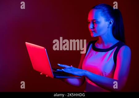 Digitale Geschäftsfrau, die in Neon an einem Laptop arbeitet Stockfoto