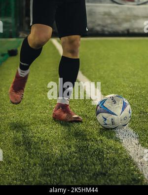 Nahaufnahme der Füße eines Fußballers und eines Balls auf einem Grasfeld Stockfoto
