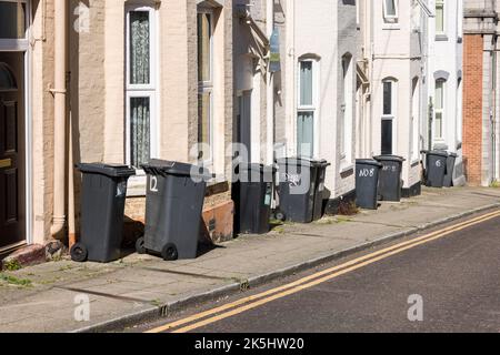 BOURNEMOUTH, Großbritannien - 08. Juli 2022. Reihe von Mülltonnen auf dem Bürgersteig vor den Häusern in einer Straße in Großbritannien Stockfoto