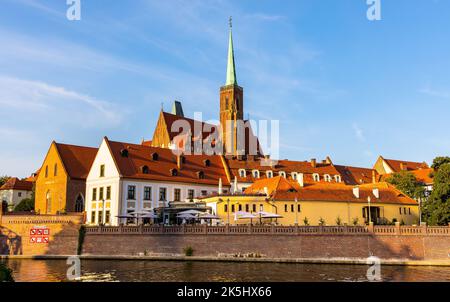 Breslau, Polen - 19. Juli 2022: Gotische Kathedrale des Heiligen Kreuzes, die sich über der Insel Ostrow Tumski und dem Fluss Odra im historischen Altstadtviertel erhebt Stockfoto