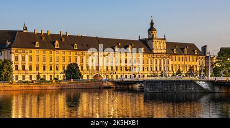 Wroclaw, Polen - 19. Juli 2022: Historisches Altstadtviertel mit Universität Wroclaw und Grodzka Straßendamm bei Sonnenuntergang über dem Fluss Warta Stockfoto