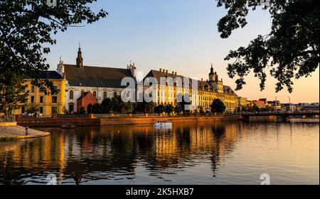 Wroclaw, Polen - 19. Juli 2022: Historisches Altstadtviertel mit Universität Wroclaw und Grodzka Straßendamm bei Sonnenuntergang über dem Fluss Warta Stockfoto