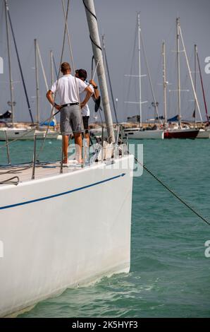 Zwei Cremen stehen auf den Bögen einer großen Luxuskreuzfahrtschacht im Hafen in Zante Stadt zakynthos in griechenland. Zwei Männer stehen auf dem Bug der Yacht. Stockfoto