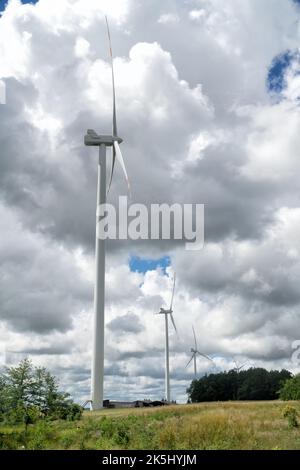 Ländliche Landschaft mit Windpark, Windmühlen für die Stromproduktion, Himmel mit stürmischen Wolken im Hintergrund. Erneuerbare Energien, Nachhaltigkeit, Stockfoto