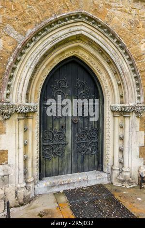 Alte, kunstvoll verzierte Kirchentür mit gotischen Bögen und mit Fleuron dekorierten Scharnieren St James Church, Little Dalby, Leicestershire, England, Großbritannien Stockfoto