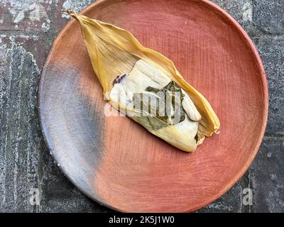 Ein Oaxacan Tamal auf einem Teller mit masa und hierba santa Stockfoto