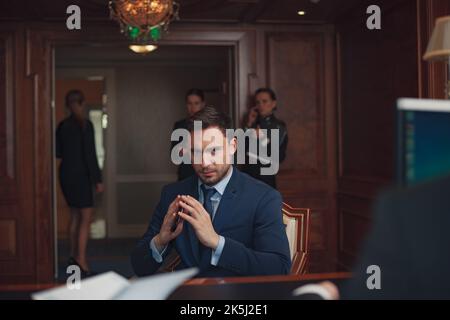 Ein gutaussehender Geschäftsmann in Anzug im Hotel checke an der Rezeption oder an der Rezeption ein Stockfoto