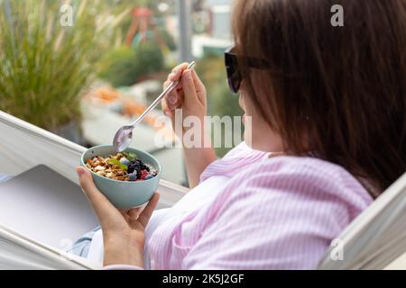 Junge Frau, die Chia-Pudding mit Nüssen und Beeren isst Stockfoto