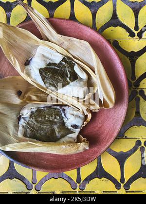 Zwei Oaxacan Tamales auf einem Teller auf einem gelben Musterhintergrund Stockfoto