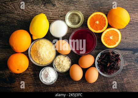 Upside Down Blood Orange, Hibiscus und Polenta Cake Zutaten: Zutaten für ein milchfreies und glutenfreies Dessert auf Holzgrund Stockfoto