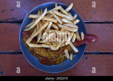 Currywurst serviert mit Pommes in einem Biergarten, Bayern, Deutschalmd Stockfoto