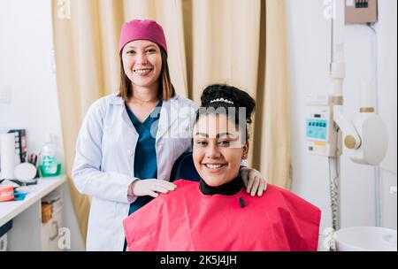 Zahnärztin mit zufriedenem Patienten lächelt an der Kamera, Zahnärztin mit Patient lächelt freundlich. Porträt eines Zahnarztes mit lächelndem Patienten Stockfoto