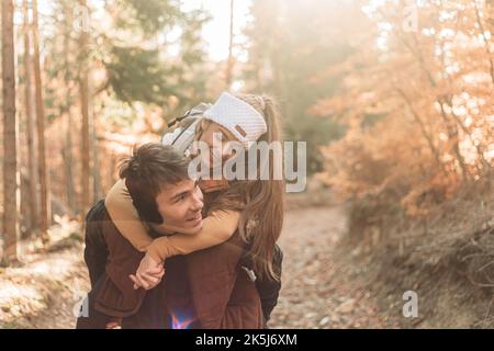 Junges romantisches Paar im Wald. Huckepack Reiten. Glücklich zusammen Stockfoto