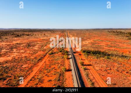 Entferntes australisches Outback mit roter Erde und einer einzigen Eisenbahnlinie zur Stadt Broken Hill - Luftaufnahme der Landschaft. Stockfoto