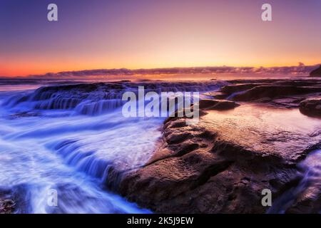 Malerischer, farbenfroher Sonnenaufgang am Whale Beach von Sydney Northern Beaches an der Pazifikküste Australiens mit überfließenden Felsen. Stockfoto