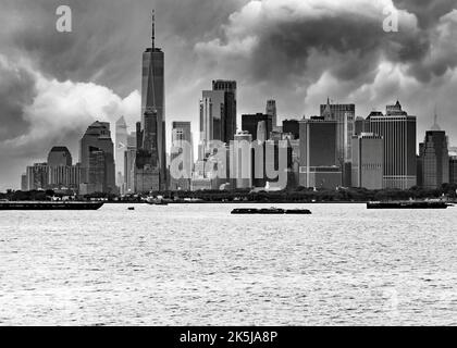 Skyline von Downtown Manhattan mit launischem Himmel im Hintergrund und Hafen und Fluss im Vordergrund in Schwarz und Weiß Stockfoto