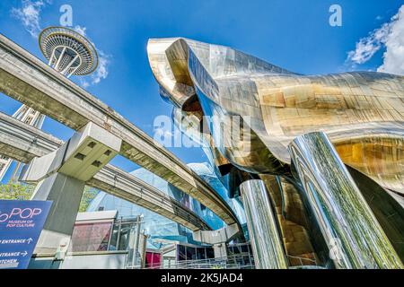 Die Monorail-Strecken von der Seattle World’s Fair mit Space Needle hinter sich führen in das Museum of Pop Culture in Seattle, Washington. Stockfoto