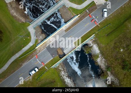 Luftaufnahme der beschädigten Straßenbrücke über den Fluss, nachdem das Hochwasser den Asphalt weggespült hatte. Wiederaufbau der zerstörten Verkehrsinfrastruktur. Stockfoto