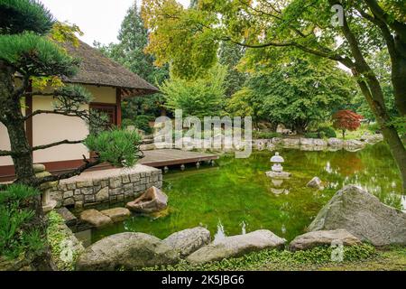 Teehaus und Teich und Laterne und Spiegelungen im japanischen Garten des Botanischen Gartens 'Planten un Blomen' in Hamburg. Frühherbst im Norden Stockfoto