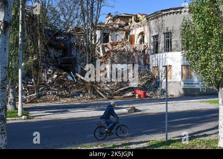 Slowiansk, Donezk, Ukraine. 8. Oktober 2022. Ein Mann fährt mit dem Fahrrad an einem Wohngebäude vorbei, das durch einen russischen Beschuss in Sloviansk schwer beschädigt wurde. In den letzten Wochen hat die ukrainische Armee in einer erfolgreichen Gegenoffensive große Teile des Territoriums zurückerobert, die russische Truppen gezwungen hat, lange gehaltene Positionen aufzugeben. In dem, was Kiew als Moskaus Reaktion auf seine Niederlagen beschreibt, hat Präsident Wladimir Putin vier teilweise besetzte Regionen der Ukraine eingegliedert. Die Annexionen, die weithin als illegal abgetan wurden, haben Befürchtungen über eine mögliche Eskalation im siebenmonatigen Krieg geweckt. (Bild: © A Stockfoto