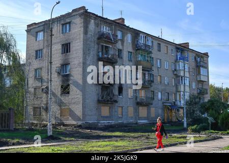 Slowiansk, Donezk, Ukraine. 8. Oktober 2022. Eine Frau kommt an einem Wohngebäude vorbei, das durch einen russischen Beschuss in Sloviansk schwer beschädigt wurde. In den letzten Wochen hat die ukrainische Armee in einer erfolgreichen Gegenoffensive große Teile des Territoriums zurückerobert, die russische Truppen gezwungen hat, lange gehaltene Positionen aufzugeben. In dem, was Kiew als Moskaus Reaktion auf seine Niederlagen beschreibt, hat Präsident Wladimir Putin vier teilweise besetzte Regionen der Ukraine eingegliedert. Die Annexionen, die weithin als illegal abgetan wurden, haben Befürchtungen über eine mögliche Eskalation im siebenmonatigen Krieg geweckt. (Bild: © Andriy An Stockfoto