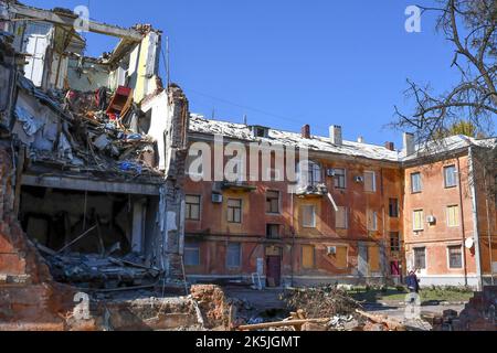 Slowiansk, Donezk, Ukraine. 8. Oktober 2022. Anwohner gehen auf den Hof eines Gebäudes, das durch einen russischen Beschuss in Slowjansk schwer beschädigt wurde. In den letzten Wochen hat die ukrainische Armee in einer erfolgreichen Gegenoffensive große Teile des Territoriums zurückerobert, die russische Truppen gezwungen hat, lange gehaltene Positionen aufzugeben. In dem, was Kiew als Moskaus Reaktion auf seine Niederlagen beschreibt, hat Präsident Wladimir Putin vier teilweise besetzte Regionen der Ukraine eingegliedert. Die Annexionen, die weithin als illegal abgetan wurden, haben Befürchtungen über eine mögliche Eskalation im siebenmonatigen Krieg geweckt. (Bild: © Stockfoto