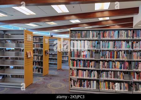 Reihen von Bücherregalen mit Büchern und Lehrbüchern in der öffentlichen Bibliothek. Lern- und Bildungskonzept. Stockfoto