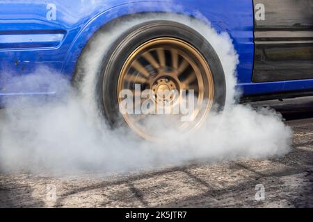 Ziehen Sie den brennenden Reifen des Rennwagens an der Startlinie auf der Rennstrecke Stockfoto