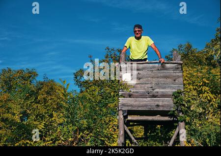 Blick aus der unteren Perspektive auf einen älteren Mann, der auf dem hölzernen Jagdschloss steht Stockfoto