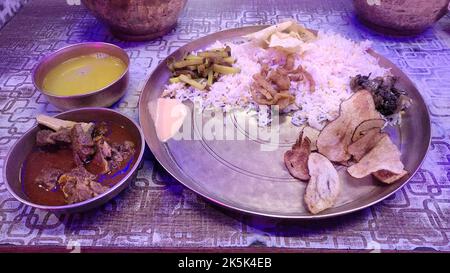 Traditionelles nepalesisches Thali, serviert auf einer Messingplatte mit Reis, Fleischcuru, Linsen und anderen Beilagen. Grundnahrungsmittel für die nepalesische Kultur. Stockfoto