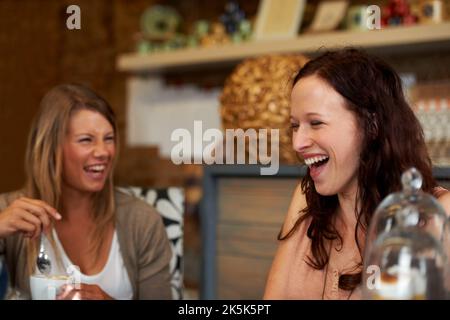 Nachholbedarf in alten Zeiten. Zwei Freundinnen lachen gemeinsam, während sie in einem Café sitzen. Stockfoto