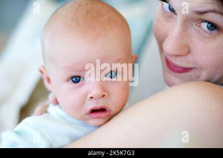 Schalt meine Mutter und meine. Porträt einer Mutter mit ihrem Baby, das über ihre Schulter schaut. Stockfoto