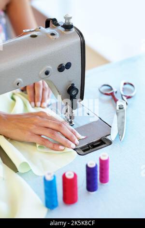 Nähmaschinen sind in dieser Branche ein muss. Beschnittenes Bild einer ethnischen Frau Hände, während sie eine Nähmaschine bei der Arbeit verwendet. Stockfoto