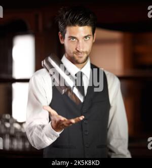 Hes a Master Cocktail Mixer. Porträt eines hübschen jungen Barkeepers, der einen Cocktail für einen Kunden mixt. Stockfoto