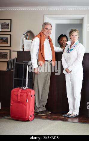 Einchecken an der Rezeption. Ein älteres Paar checkte an der Rezeption des Hotels ein. Stockfoto