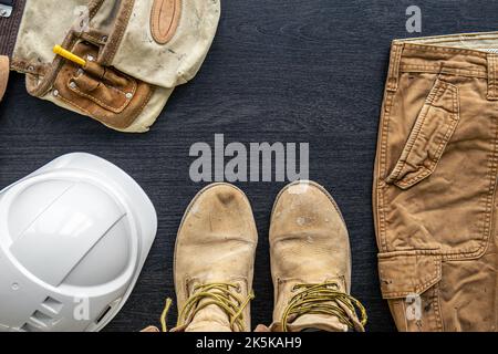 Bauherrenkleidung, Arbeitsuniform auf Holzhintergrund, flaches Lay. Stockfoto