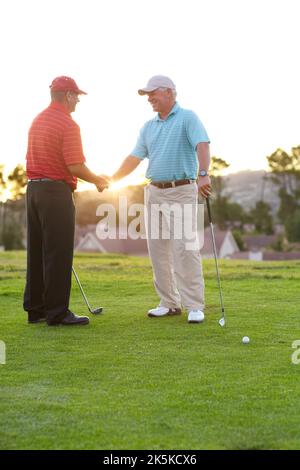 Gut gespielt. Zwei männliche Golfer schütteln sich nach einer freundlichen Runde Golf die Hände. Stockfoto