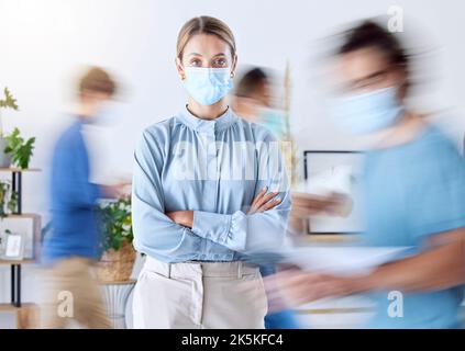 Porträt einer Geschäftsfrau im Büro während des Aufschwungs und einer Unschärfe der Menschen im Büro. Geschäftsleute, Compliance und tragen Gesichtsmaske für die Sicherheit Stockfoto