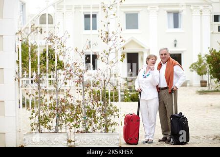 Entspannung am Ziel. Ein Seniorenpaar, das im Urlaub mit den Koffern steht. Stockfoto