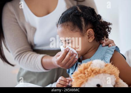 Mutter putzt kranke Kindernase mit Gewebe, spielt mit Spielzeug oder Teddybär im Schlafzimmer bei der Familie zu Hause. Die Lehrerin im Kindergarten verwendet Toilettenpapier, um zu helfen Stockfoto