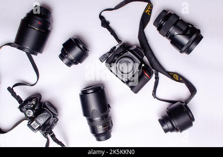 Kameraobjektiv und Gehäuse sind auf weißem Hintergrund verstreut Stockfoto
