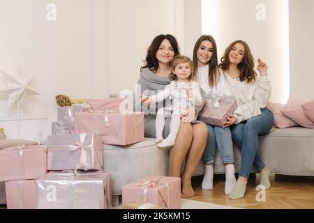 Vier Frauen unterschiedlichen Alters zur Weihnachtszeit. Von der Enkelin zur Großmutter. Geschenke auf dem Boden Stockfoto