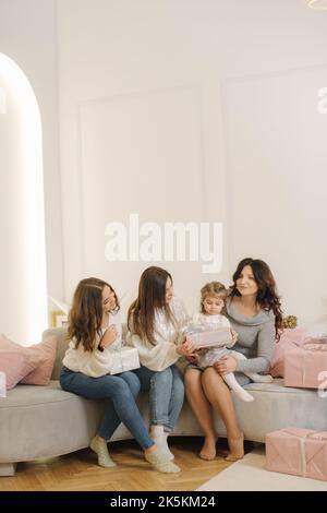 Vier Frauen unterschiedlichen Alters zur Weihnachtszeit. Von der Enkelin zur Großmutter. Geschenke auf dem Boden Stockfoto