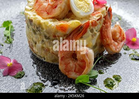 Olivier-Salat mit Garnelen und Lachs auf einem Teller Stockfoto